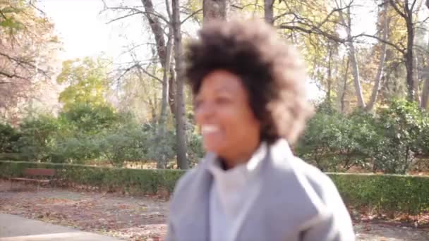 schöne Afro-Frau, die Spaß an der Kommunikation mit ihrem Smartphone im Park hat - Filmmaterial, Video