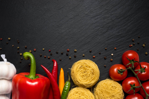 Colorful vegetables and noodles on black background with copy space. - Foto, afbeelding