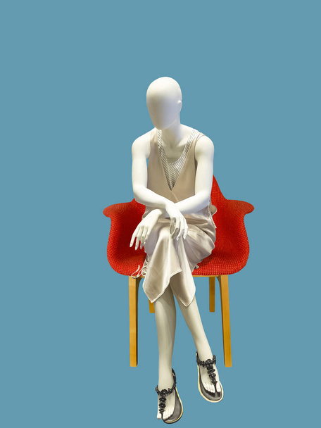 Mannequin féminin assis portant une robe à la mode, isolé sur fond bleu. Aucun nom de marque ou objet de copyright
. - Photo, image