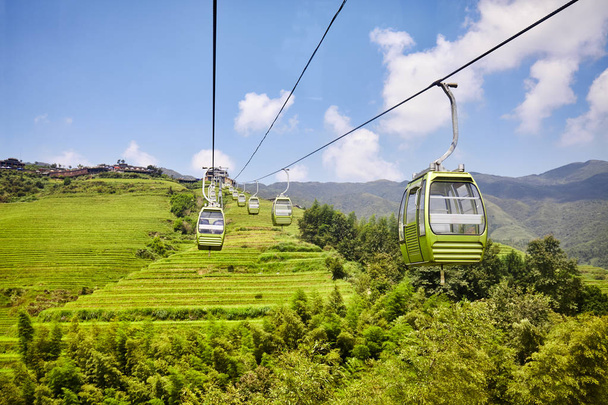 Teleférico acima dos terraços de arroz Longji (espinha dorsal do dragão), uma das principais atrações turísticas da Guilin, na China
. - Foto, Imagem