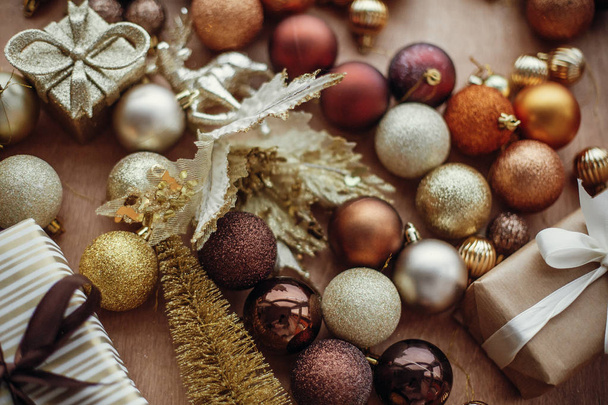 Kerst stijlvolle geschenkbox met glitter ornamenten en kerstballen op rustieke houten achtergrond. Moderne bruin en goud decoraties. Groeten van de seizoenen. Vrolijk kerstfeest - Foto, afbeelding