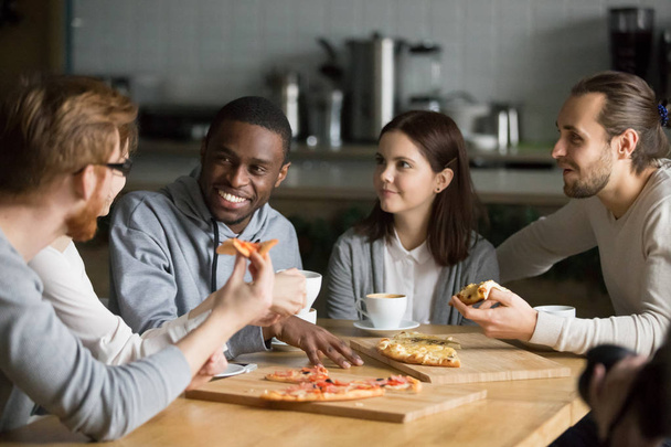 Ποικίλες φίλους να φάω πίτσα απολαμβάνοντας ενδιαφέρουσα ομιλία στο τραπέζι - Φωτογραφία, εικόνα