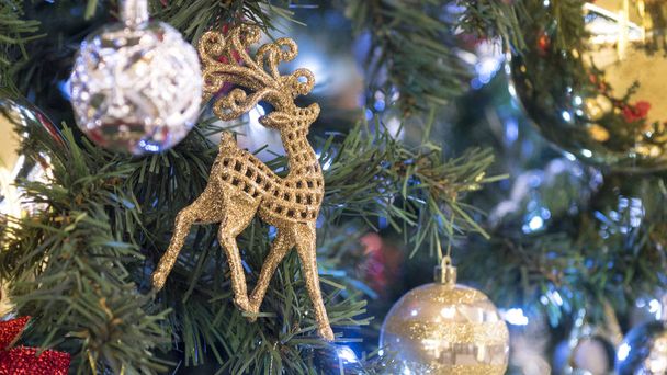 Christmas decoration: beautiful Golden deer, red and golden Christmas ball on fir tree branch. - Фото, изображение