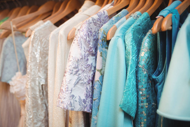 Разноцветная одежда на вешалках в бутик-магазине
 - Фото, изображение