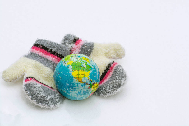 Пара в'язаних рукавиць обережно захищають планету Земна куля від холоду
 - Фото, зображення