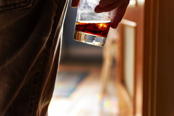 Alcoholism concept. Man entering the kitchen with a glass of whiskey in his hand.Alcoholism concept. Man entering the kitchen with a glass of whiskey in his hand. - Photo, Image
