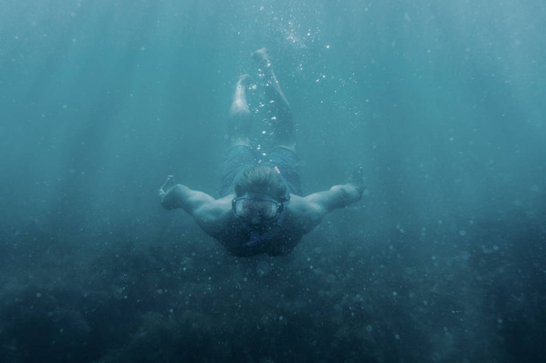 Actieve mannelijke freediver in masker onderwater, front view zwemmen. - Foto, afbeelding