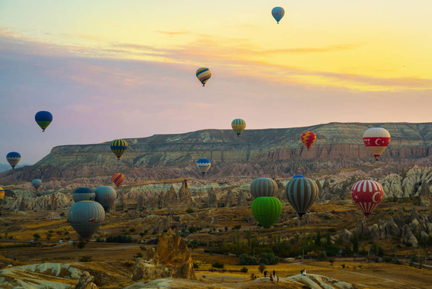 Flying on the balloons early morning in Cappadocia. Colorful spring sunrise in Red Rose valley, Goreme village location, Turkey, Asia. Traveling concept background. - Foto, Imagem