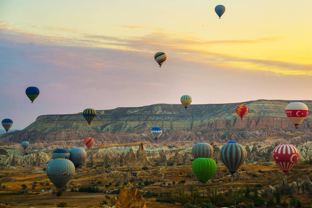 Flying on the balloons early morning in Cappadocia. Colorful spring sunrise in Red Rose valley, Goreme village location, Turkey, Asia. Traveling concept background. - Foto, Imagen