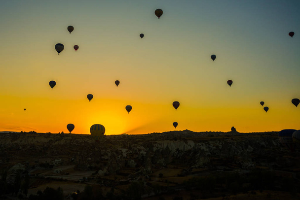 Cappadocia, Goreme, Anatolia, Turkey: Hot air balloon ride sunset silhouettes view. Sunset hot air balloon silhouette. Sunset hot air balloon sky silhouette. Hot air ballon silhouete - Фото, зображення