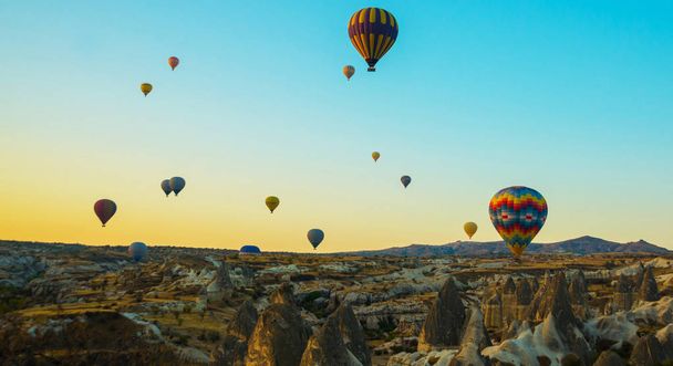 Colorful balloons against the morning sky and beautiful rocky valleys. The great tourist attraction of Cappadocia - balloon flight. Goreme, Cappadocia, Turkey. - Fotoğraf, Görsel