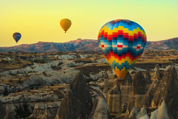 Πολύχρωμα μπαλόνια κατά τον ουρανό το πρωί και τα όμορφα βραχώδη κοιλάδες. Το μεγάλο τουριστικό αξιοθέατο της Καππαδοκίας - Αεροστάτου. Γκιόρεμε, Καππαδοκία, Τουρκία. - Φωτογραφία, εικόνα