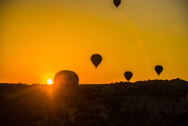 Silhouette of hot air balloons flying over the valley at Cappadocia, Anatolia, Turkey. Volcanic mountains in Goreme national park. Favorite entertainment for tourists. - Фото, изображение