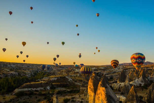 Cappadocia, Goreme, Anatolia, Turkey. Bright multi-colored hot air balloons flying in sunsrise sky Cappadocia. Favorite entertainment for tourists. - Fotografie, Obrázek