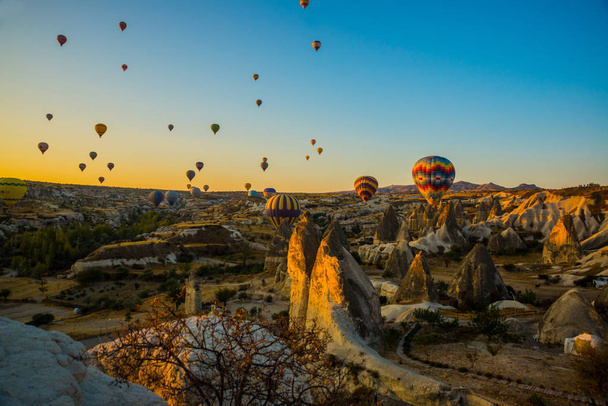 Cappadocia, Goreme, Anatolia, Turkey. Bright multi-colored hot air balloons flying in sunsrise sky Cappadocia. Favorite entertainment for tourists. - Foto, afbeelding