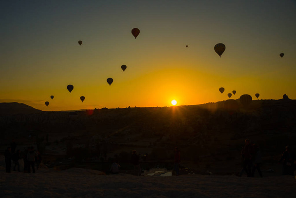 Silhouette of hot air balloons flying over the valley at Cappadocia, Anatolia, Turkey. Volcanic mountains in Goreme national park. Favorite entertainment for tourists. - Φωτογραφία, εικόνα