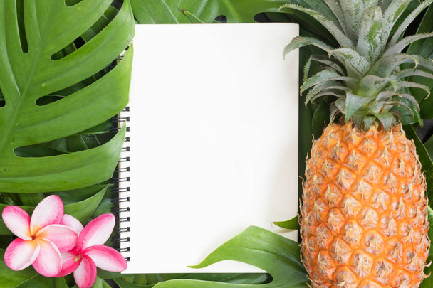 Tropical top view summer botanical concept still life white frame notebook and pineapple with monstera liana, vine, palm leaves and plumeria frangipani flower flat lay layout - Photo, Image