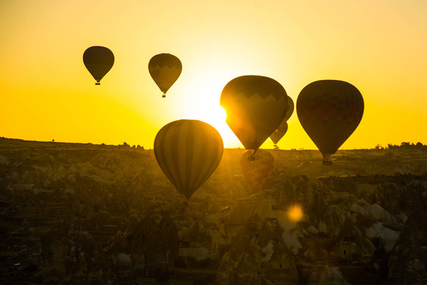 Cappadocia, Goreme, Anatolia, Turkey: The silhouette of the balloon against the yellow sky. Beautiful dawn in the valleys. Favorite entertainment for tourists. - Fotografie, Obrázek