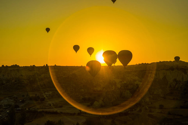 Cappadocia, Goreme, Anatolia, Turkey: The silhouette of the balloon against the yellow sky. Beautiful dawn in the valleys. Favorite entertainment for tourists. - Фото, изображение