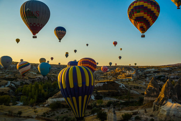 Hot air balloons take off at sunrise over Cappadocia, Goreme, Turkey. Cappadocia is known around the world as one of the best places to fly with hot air balloons. - Fotografie, Obrázek