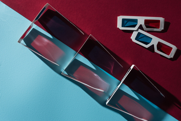 top view of 3d glasses with shadows on blue and bordo background - Photo, Image