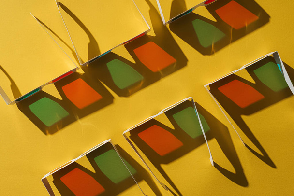vista superior de gafas 3D de cartón en dos filas con sombras sobre fondo amarillo
 - Foto, imagen