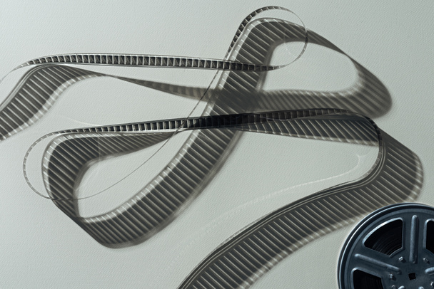 vista superior del carrete de película con cinta de cine retorcida sobre fondo gris
 - Foto, imagen
