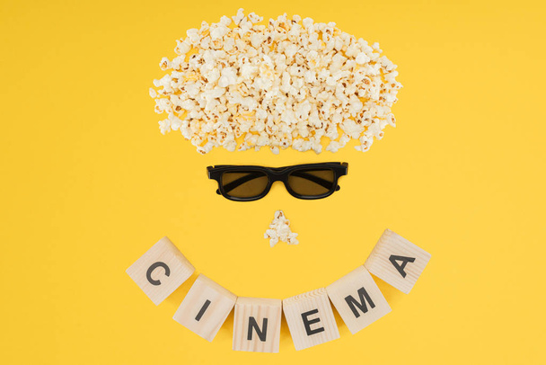 stereoscopic 3d glasses, popcorn and cubes with "cinema" lettering isolated on yellow - Photo, Image