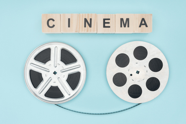 ξύλινα κυβάκια με «σινεμά» κυλίνδρους γραμμάτων και του κινηματογράφου με την κινηματογραφική ταινία μεταξύ τους απομονώνονται σε μπλε - Φωτογραφία, εικόνα