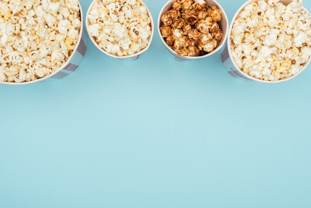 top view of buckets with popcorn in horizontal row isolated on blue - Valokuva, kuva