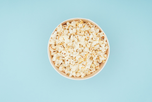 top view of bucket with fresh tasty popcorn isolated on blue - Foto, immagini