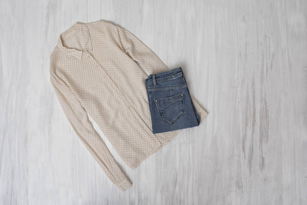 Concepto de moda. Blusa y jeans beige sobre fondo de madera. Armario femenino
 - Foto, Imagen