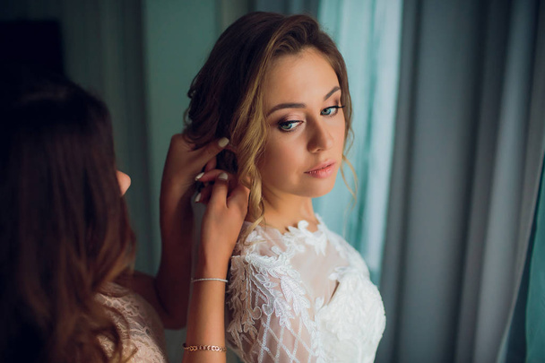 Girlfriend puts on an earring bride. Young wife. Girl in wedding dress and with wedding puts - Photo, Image