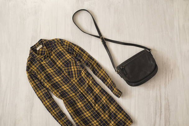 Yellow chekcered shirt with handbag on wooden background. Fashionable concept - Fotografie, Obrázek