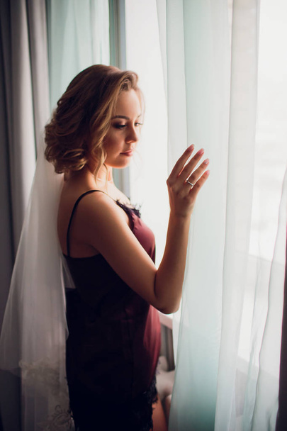 fille dans un voile de mariage près d'une fenêtre dans une chambre sombre
 - Photo, image