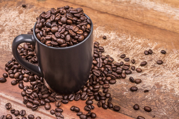 Cup of Coffee beans over a wooden background - Foto, Bild