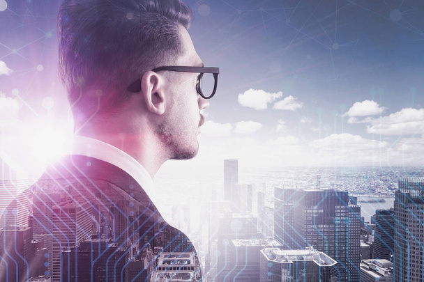 Rear view of young businessman in glasses looking at cityscape with double exposure of circuits and network hologram. Toned image - Foto, immagini