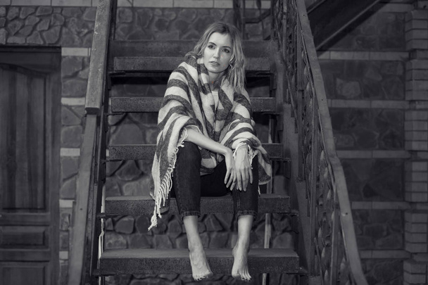 Czarno-białe zdjęcie, Portret młodej dziewczyny, siedząc na schodach w domu. - Zdjęcie, obraz