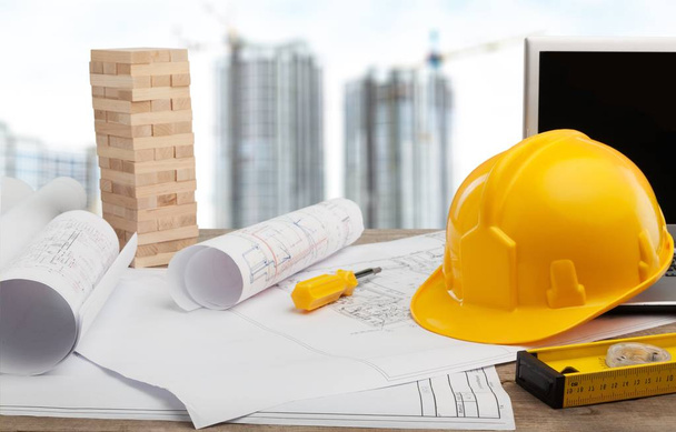 Architect workplace - architectural project, blueprints and yellow hard hat . Construction concept. Engineering tools  - 写真・画像