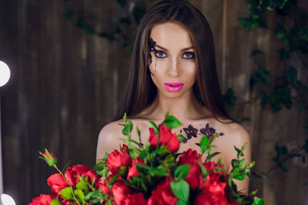 Young beautiful pretty girl standing and holding box with red roses. Vogue fashion style studio portrait girl in black elegant dress standing - Photo, Image