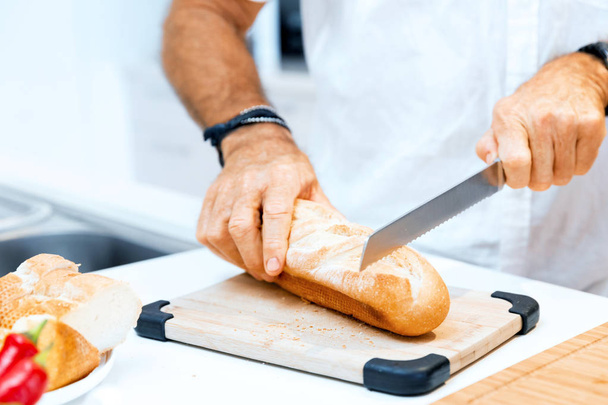 Male hands cutting bread - Fotó, kép