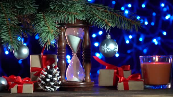 Karácsonyi háttér Xmas elemek, fenyő, gyertya égők, óra, ajándék, ragyogó fények és más új évet dekorációt. 4 k felbontású forgatták - Felvétel, videó