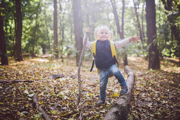 Тема активного відпочинку на природі. Смішні кавказьких Блондинка Дівчинка прогулянки прогулянки, походи в ліс по пересіченій місцевості з великими рюкзак. Використовує тростиною - Фото, зображення