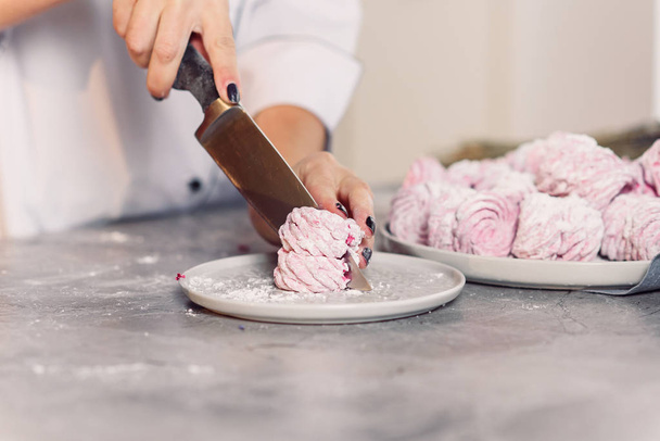 Close up chef's hand cutting freshly made marshmallows with a knife. Checking quality of homemade marshmallow. - Foto, Imagen