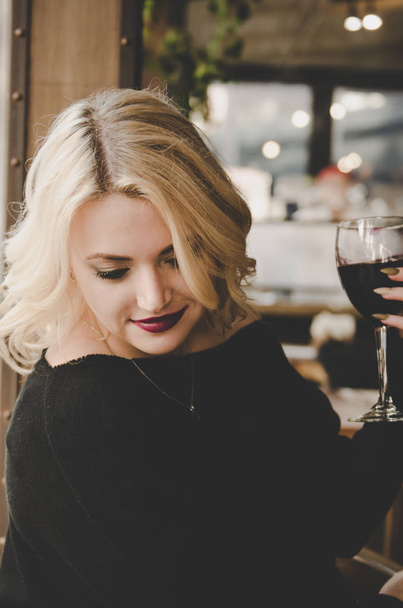 schöne junge attraktive Frau sitzt im Café und trinkt Rotwein - Foto, Bild