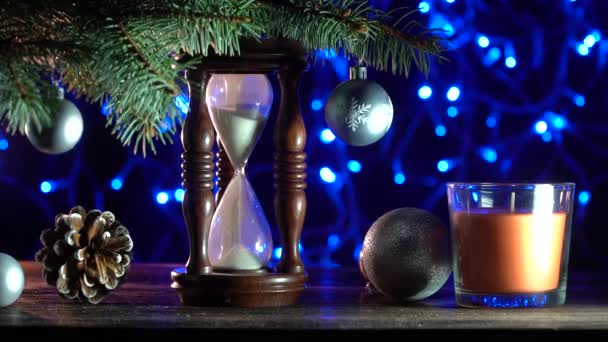 Christmas background, a sand clock under a fir tree, indicating how long it is until the New Year. Xmas Decorations. Top view. Filmed in 4k resolution - Footage, Video