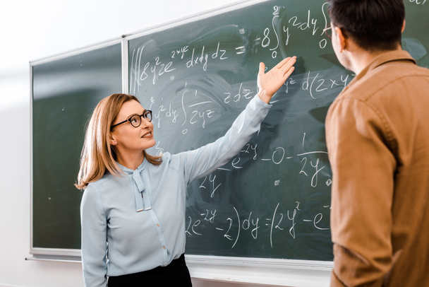 Female professor showing equations in classroom  - Foto, Imagen