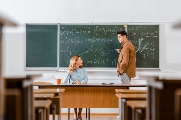 estudiante masculino mirando al profesor femenino y resolviendo ecuaciones durante la lección en el aula
 - Foto, Imagen