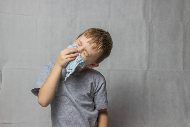 Chlapec v šedé tričko drží kapesník u nosu - Fotografie, Obrázek
