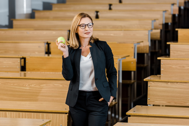 enseignante en tenue formelle tenant pomme en classe
 - Photo, image